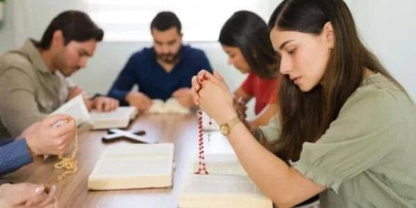 grupo y mujer joven rezando en grupo el rosario