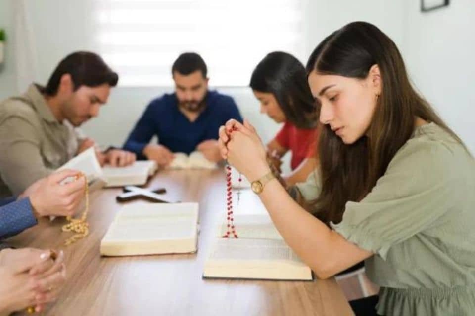 grupo y mujer joven rezando en grupo el rosario